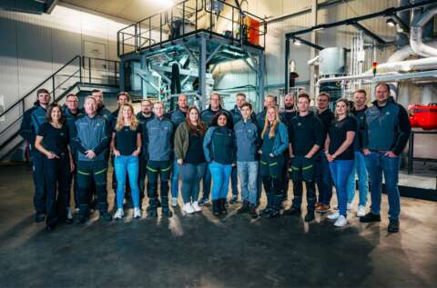 Das Team von Reckelberg Environmental Technologies im Technikum vor einem Vakuumtrockner und einem Prallreaktor, zwei Kernkomponenten für das Batterierecycling.